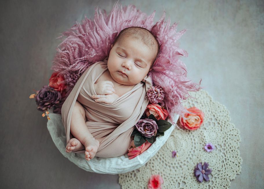 Baby im Blumenarrangement in zarten Rosatönen