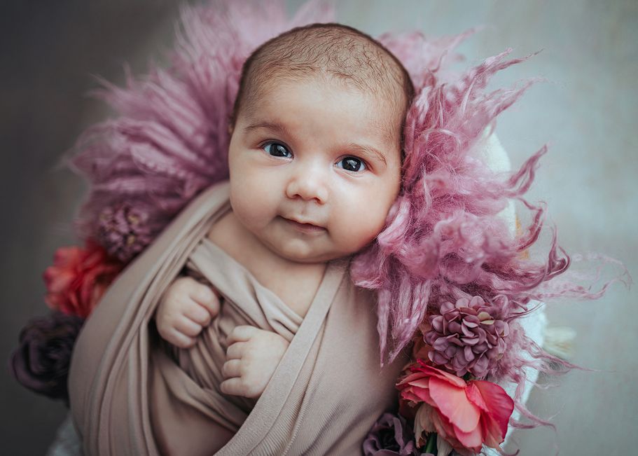 Waches Neugeborenes zwischen rosa Blüten im Körbchen - Babyfotos Dortmund