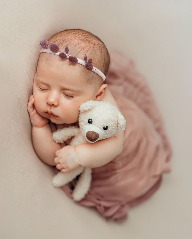 Fine-Art Newbornfoto Babyfotografie Dortmund– zarte Pose mit Teddy in Cremefarben