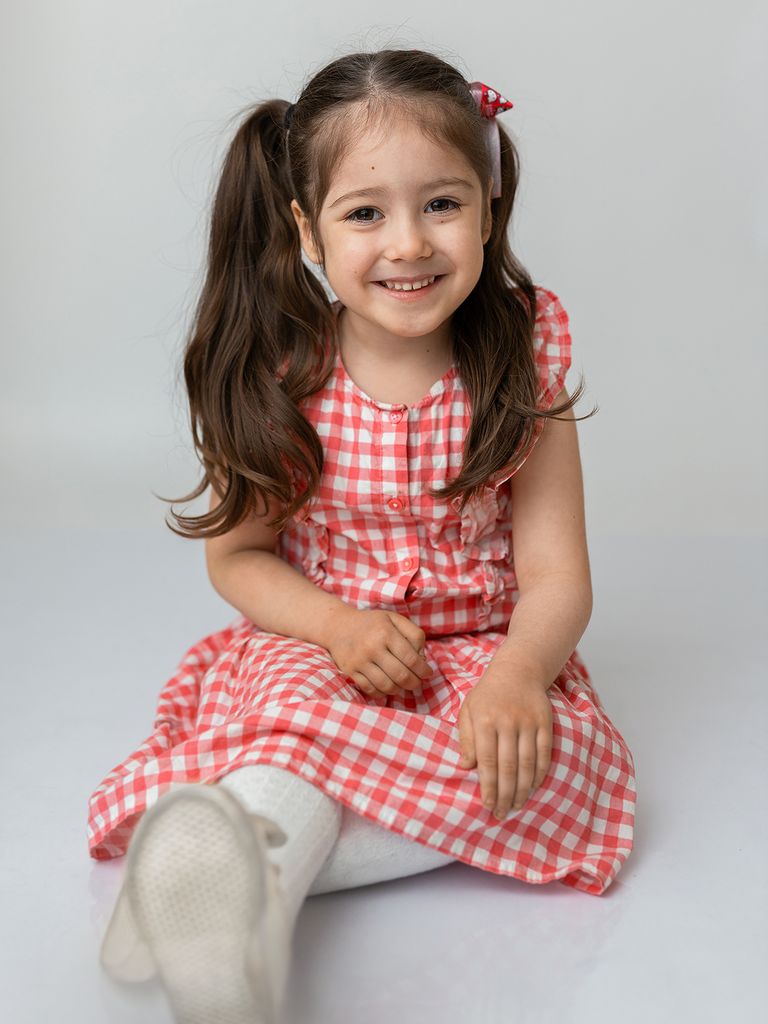 Natürliche Kinderfotografie lächelndes Mädchen im Kindergarten mit weißen Hintergrund