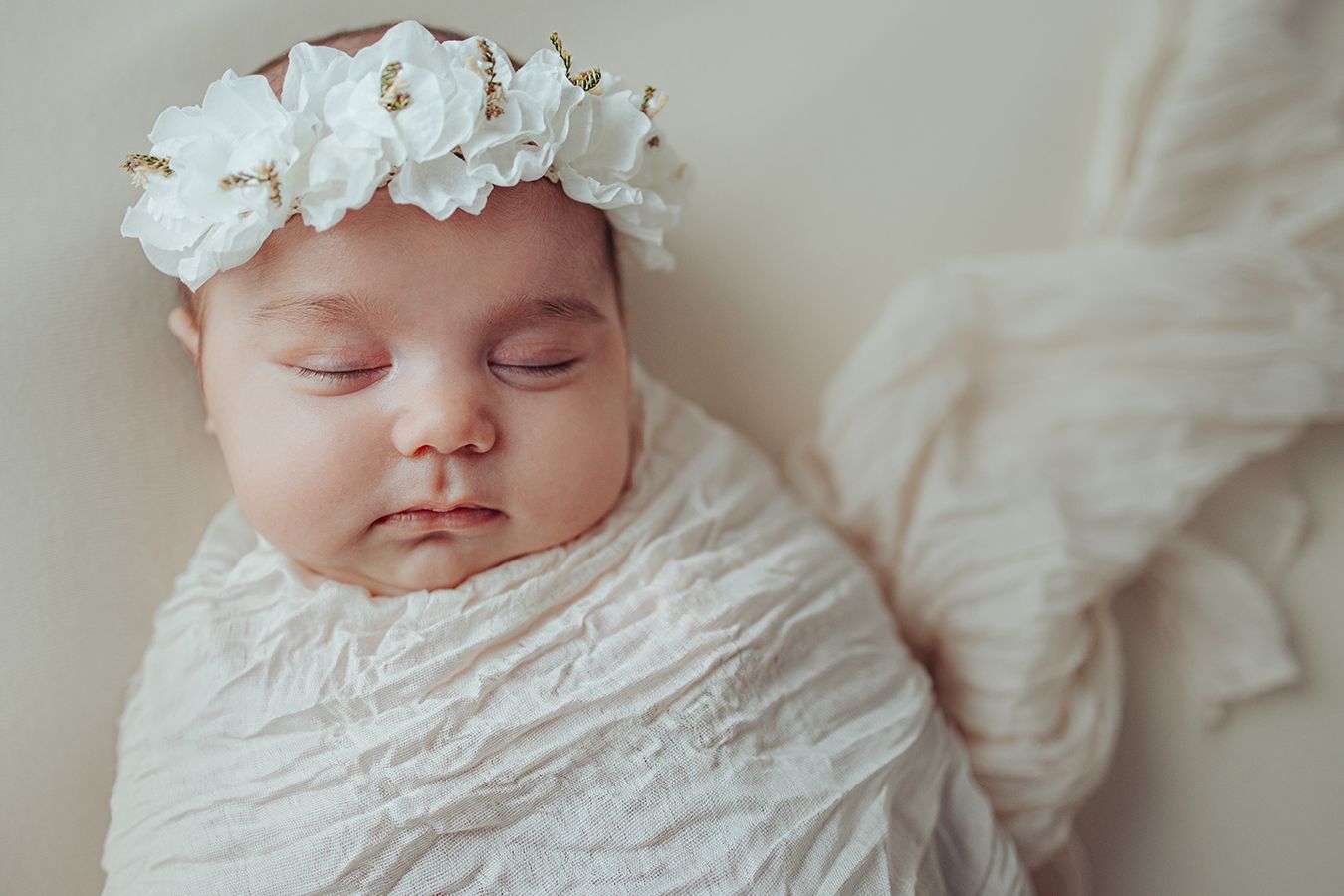 Zartes Newborn Baby eingewickelt in Stoff, natürliche Neugeborenenfotografie mit warmen Farben und ruhiger Atmosphäre