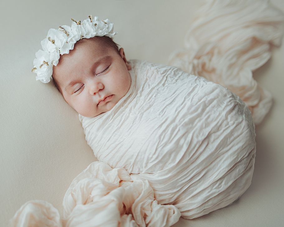 Neugeborenen Fotograf Dortmund – Baby schläft gepuckt mit Blumenkrone